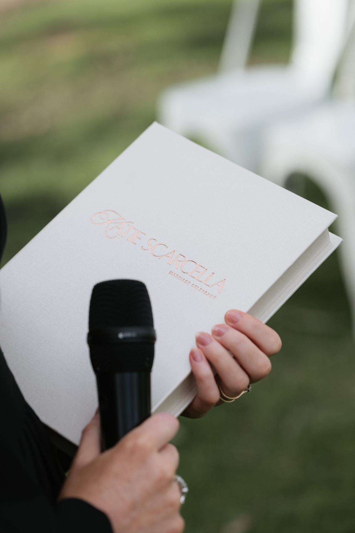 Katie’s cream iPad folio embossed with her rose-gold logo, held with a microphone